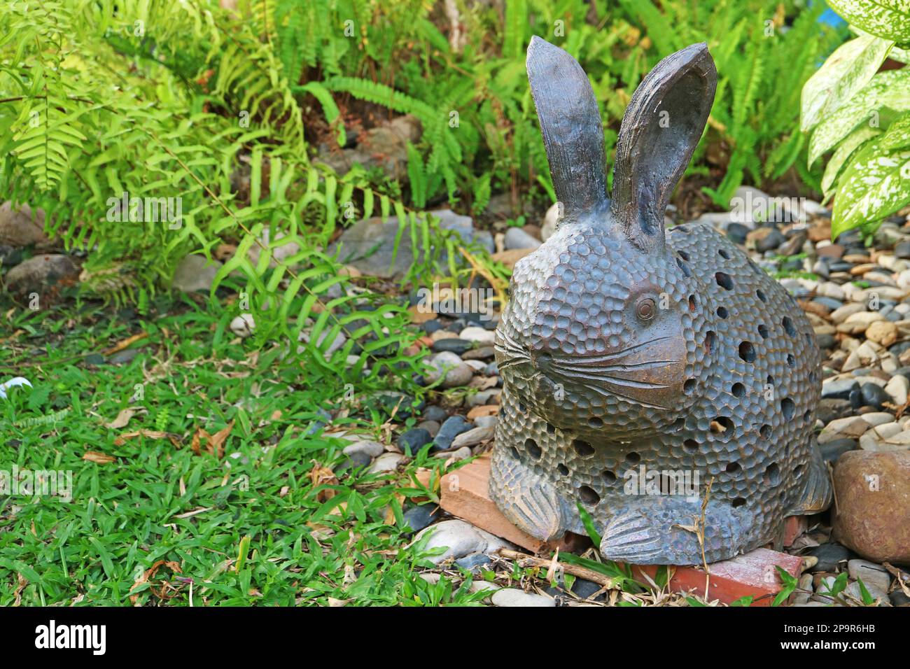 Artistic Easter Bunny Stone Figurine in the Garden Stock Photo