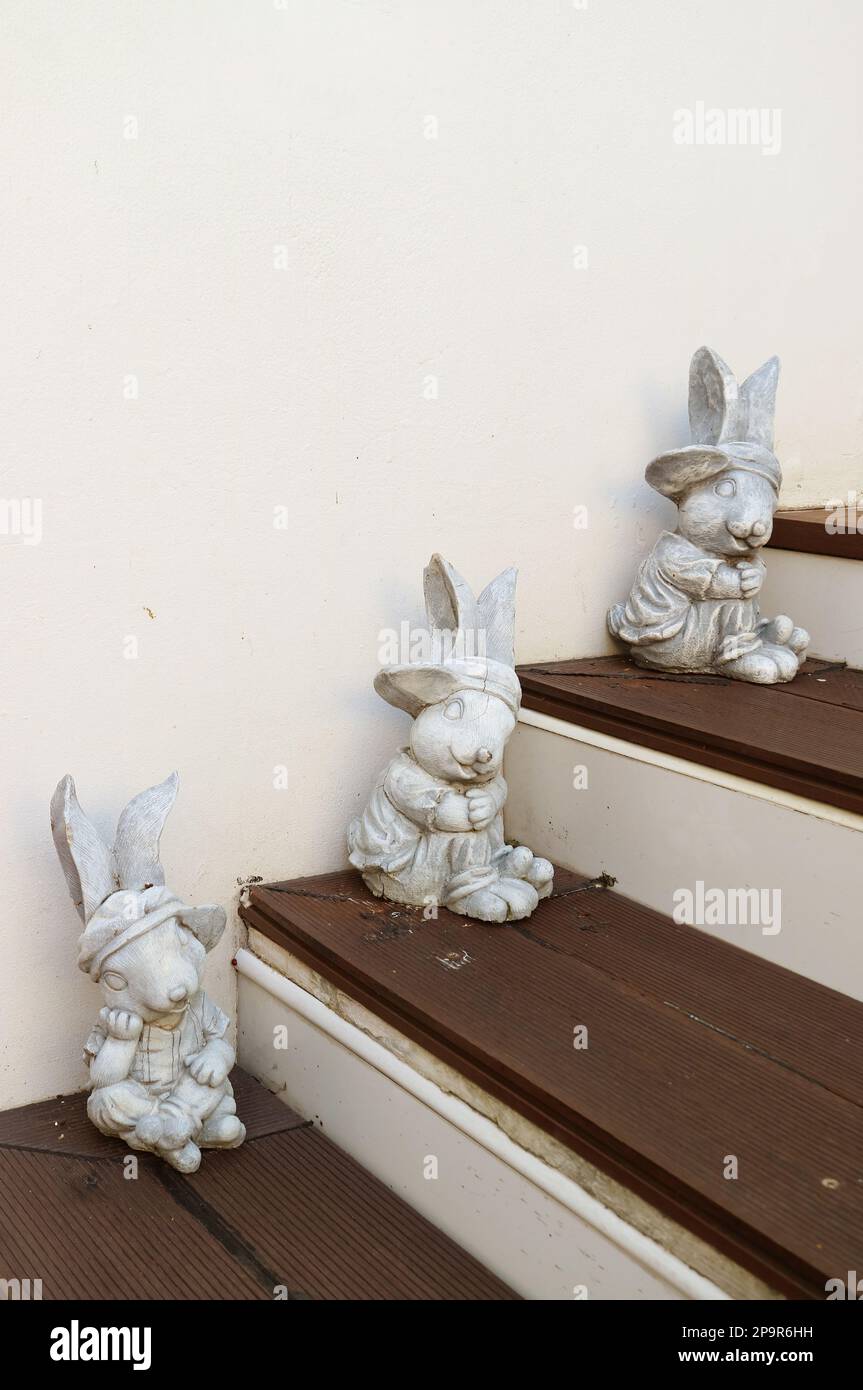Three of Adorable Easter Bunny Figurines on Wooden Steps Stock Photo