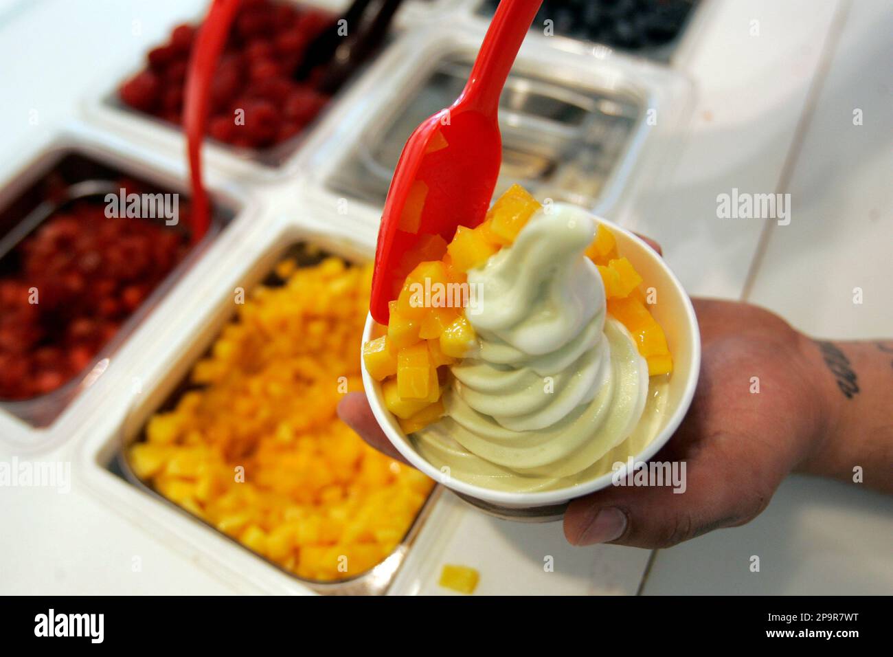 Mango pieces are dropped onto green tea frozen yogurt at a Red Mango
