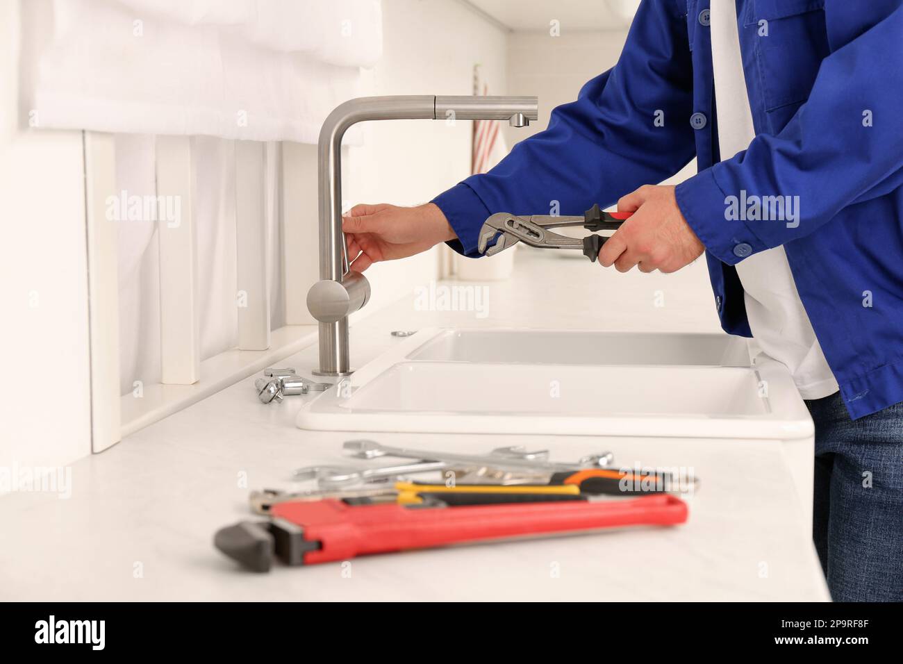 Plumber checking water tap after installation in kitchen, closeup Stock Photo