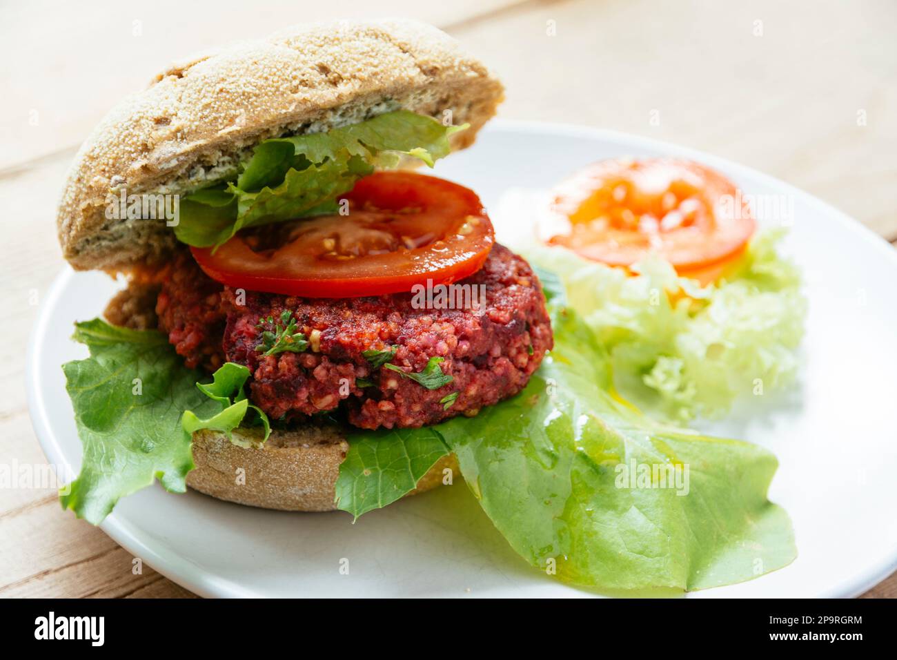 Vegan burger on a bun, made from beetroot, quinoa and lentils and raw oats as main ingredients. Stock Photo