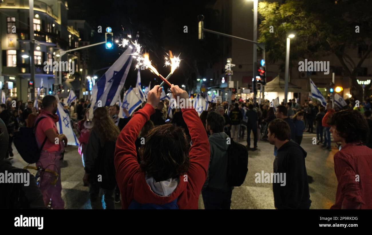 TEL AVIV, ISRAEL - MARCH 9: Anti-Government protesters hold Israeli flags as they block Allenby street during a mass demonstration against Israel's hard-right government judicial system plan that aims to weaken the country's Supreme Court on March 9, 2023 in Tel Aviv, Israel. Stock Photo
