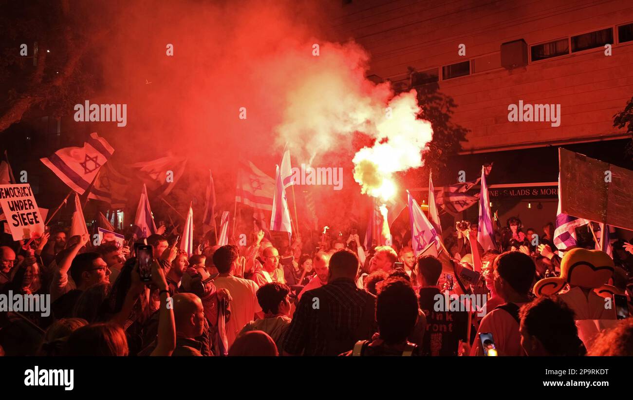 TEL AVIV, ISRAEL - MARCH 9: Anti-Government protesters chant slogans as they let off red smoke flare during a demonstration against Israel's hard-right government judicial system plan that aims to weaken the country's Supreme Court on March 9, 2023 in Tel Aviv, Israel. Stock Photo