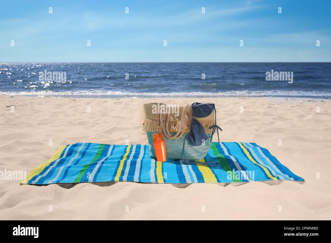 Striped beach towel and bag with accessories on sandy seashore Stock ...