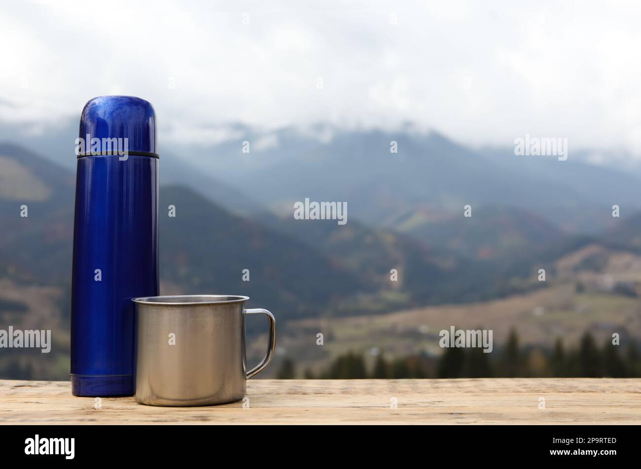 View on the blue thermos on the wooden table on the trekking trail