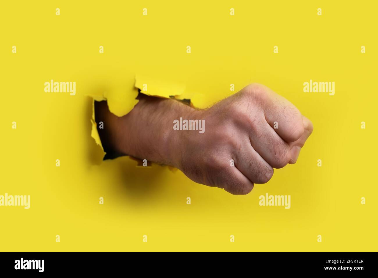 Man breaking through yellow paper with fist, closeup Stock Photo