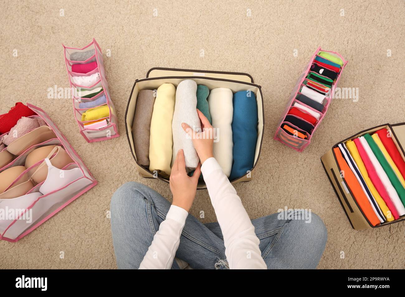 Woman folding clothes on floor, top view. Japanese storage system Stock