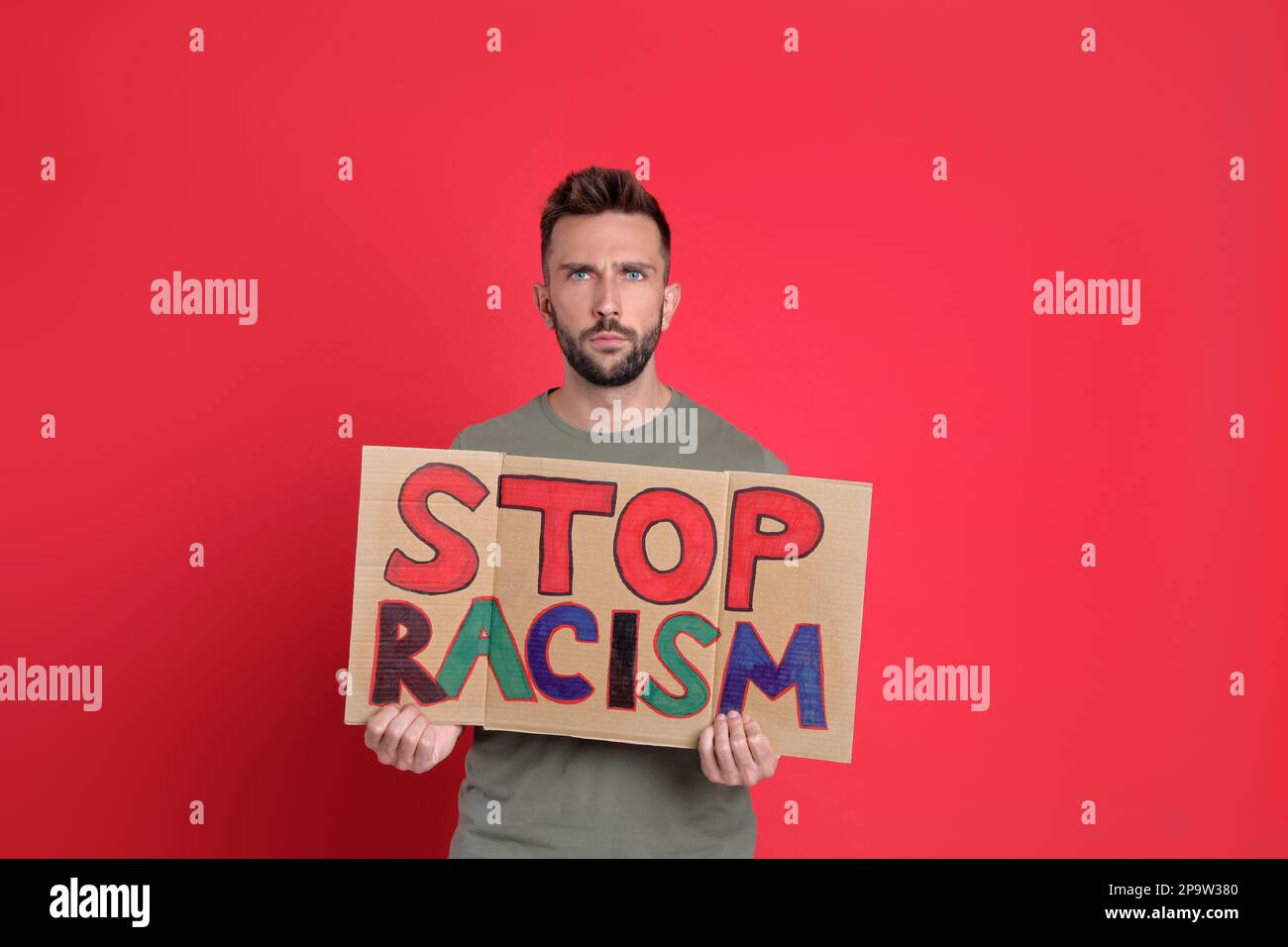 Man holding sign with phrase Stop Racism on red background Stock Photo