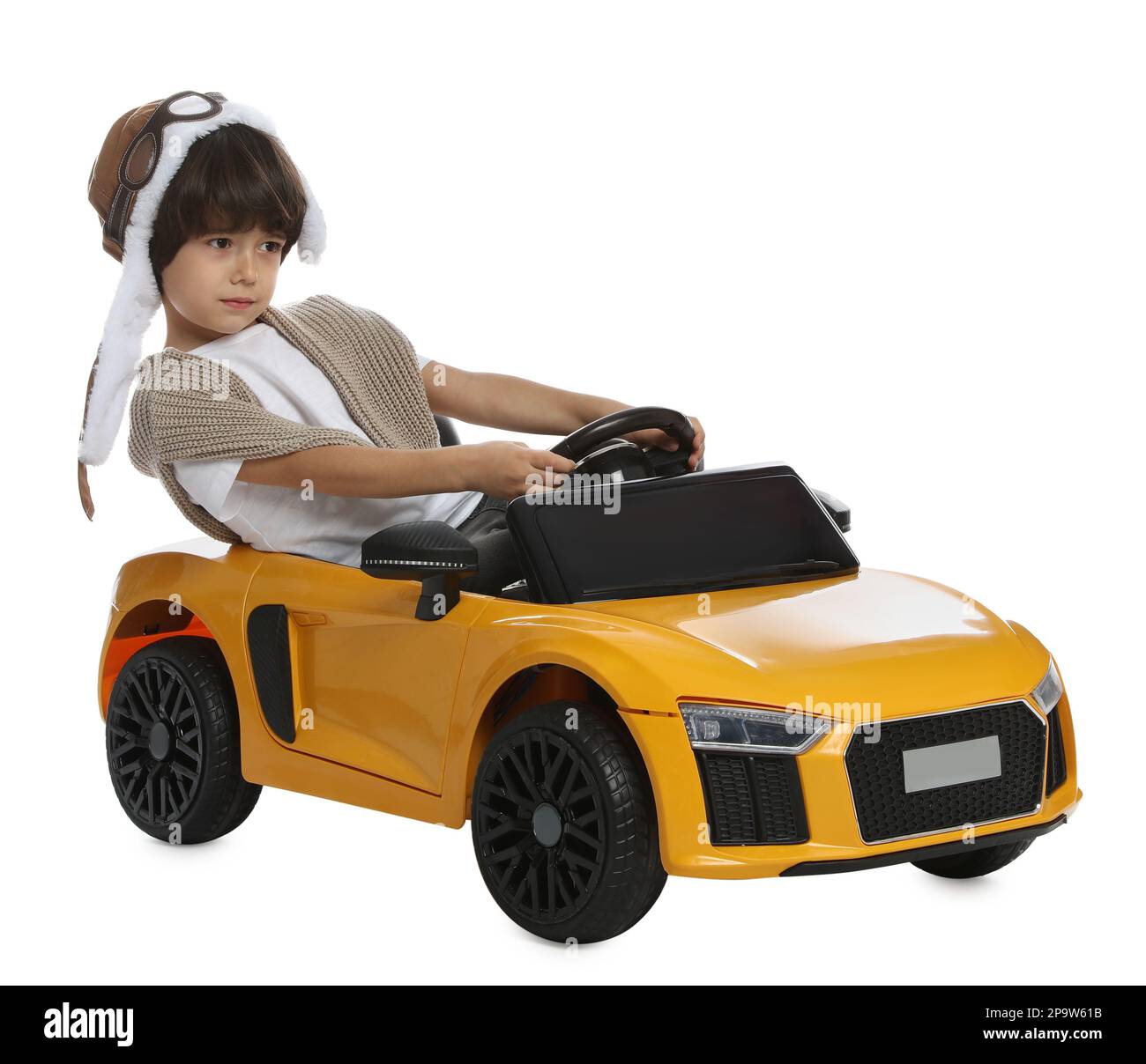 Cute little boy in pilot hat driving children's electric toy car on