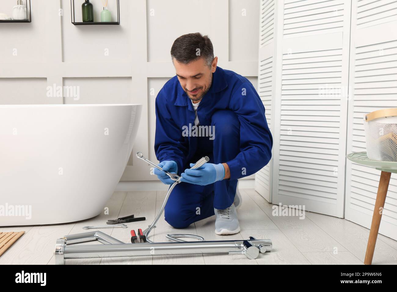 Professional plumber installing water tap in bathroom Stock Photo