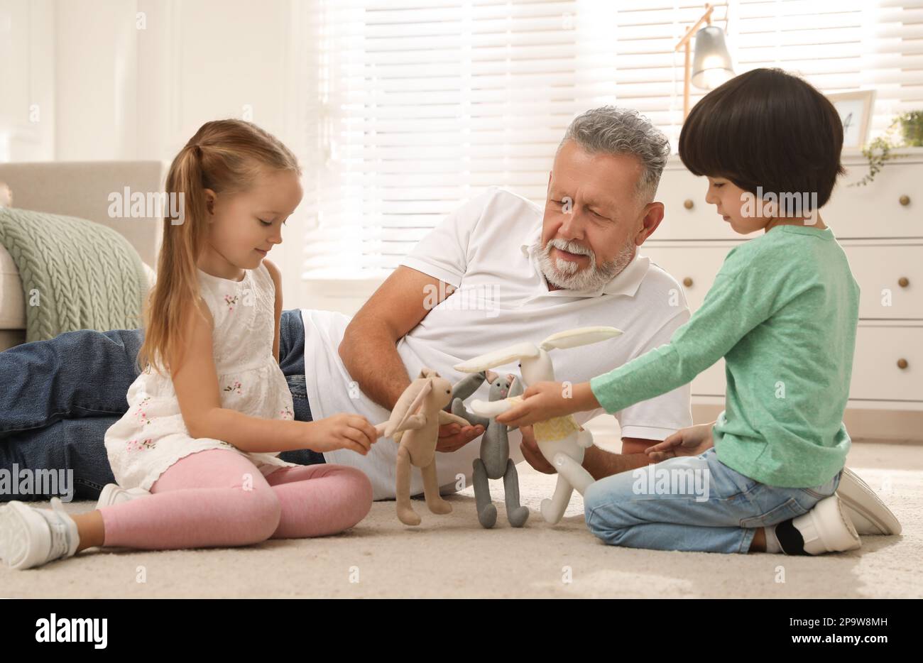 Happy grandfather and his grandchildren playing with toys together at