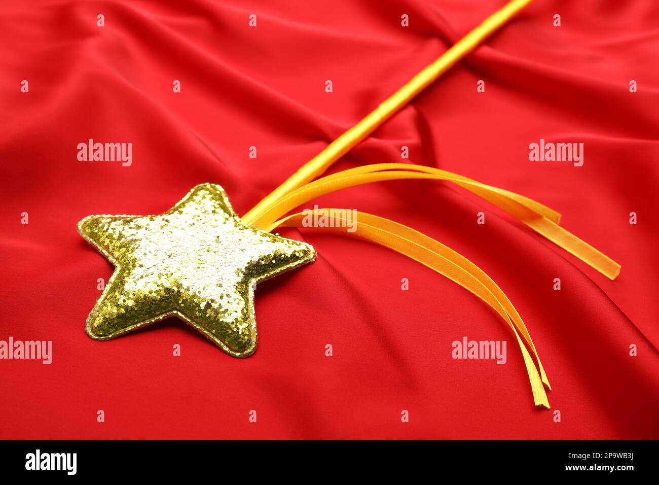 Beautiful golden magic wand on red fabric, closeup Stock Photo