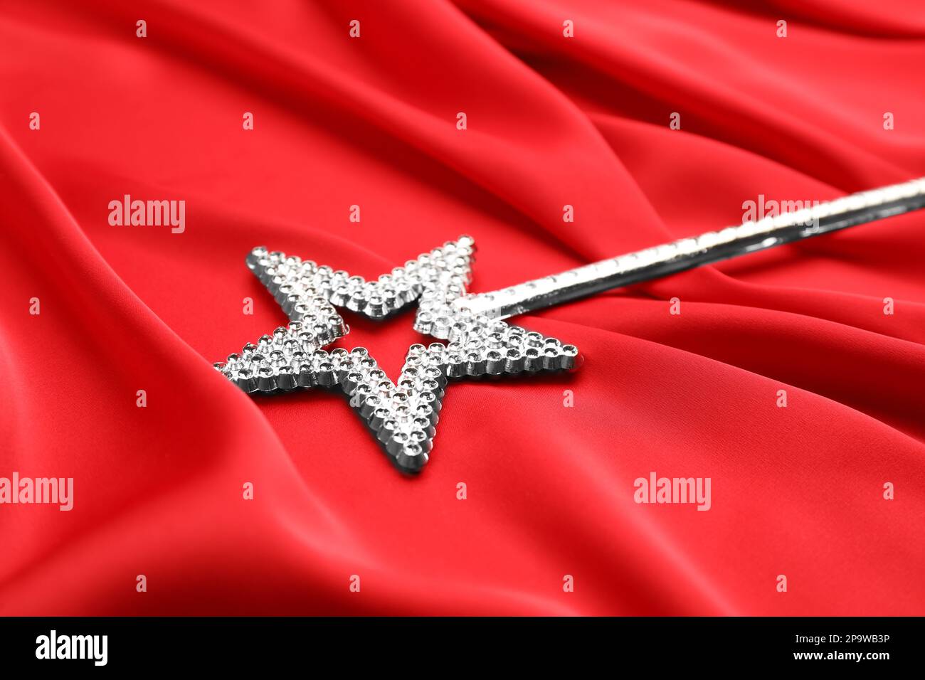 Beautiful silver magic wand on red fabric, closeup Stock Photo