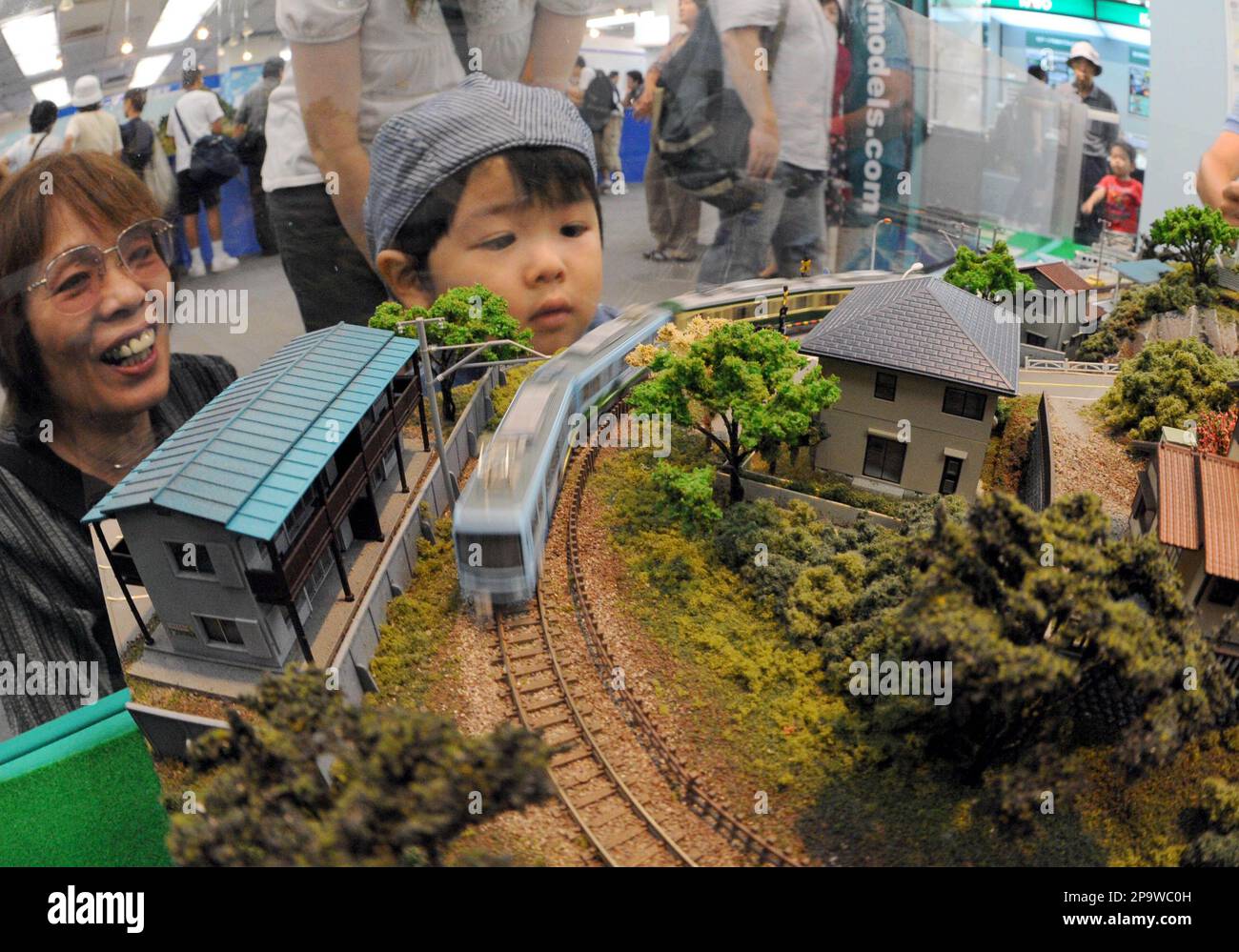 A boy and his grandmother enjoy looking at a miniature train