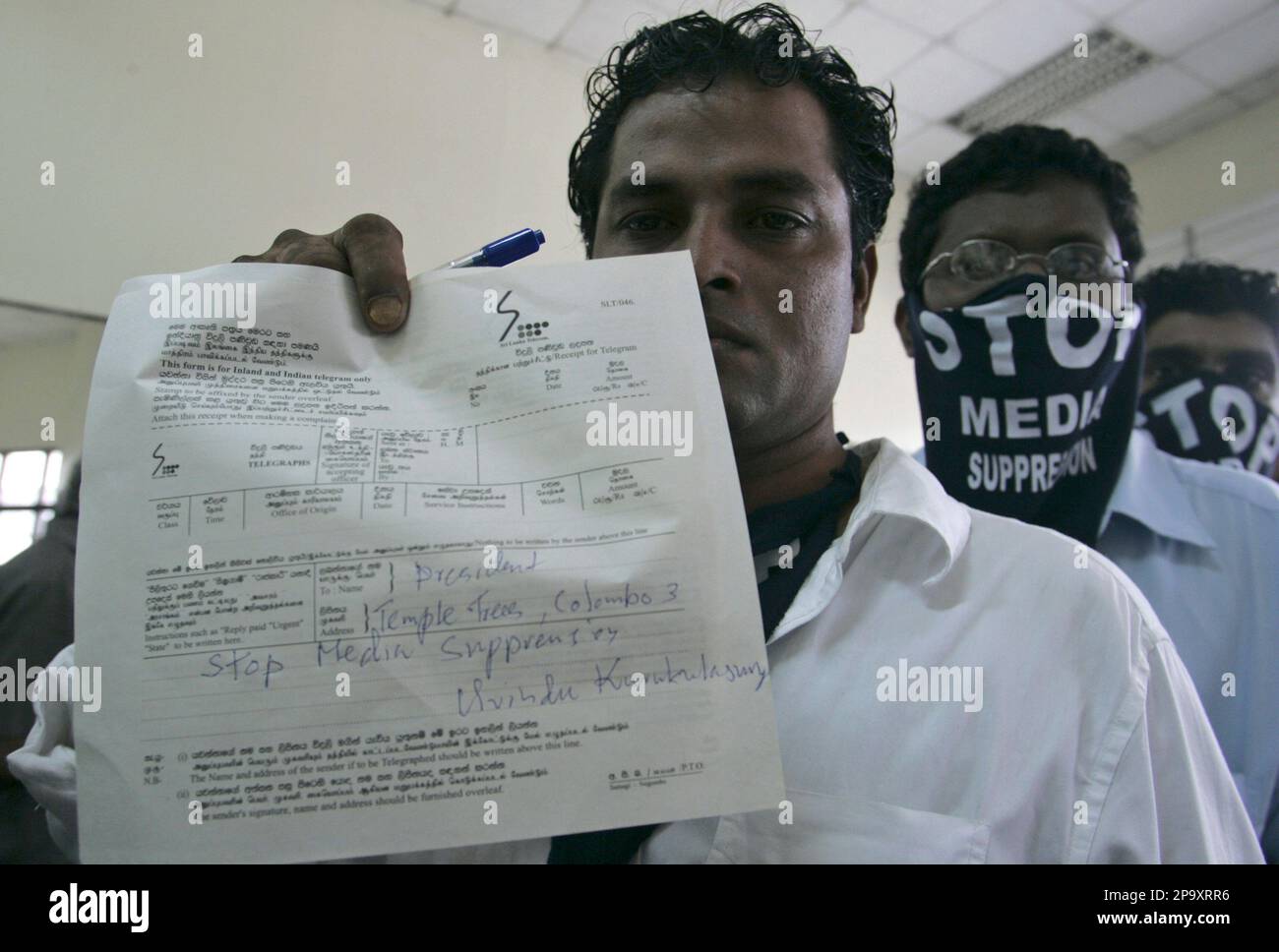 A Sri Lankan activist for media freedom holds a telegram for President  Mahinda Rajapaksa, urging him to safeguard media freedom, as others wear  masks to protest against the suppression of media at