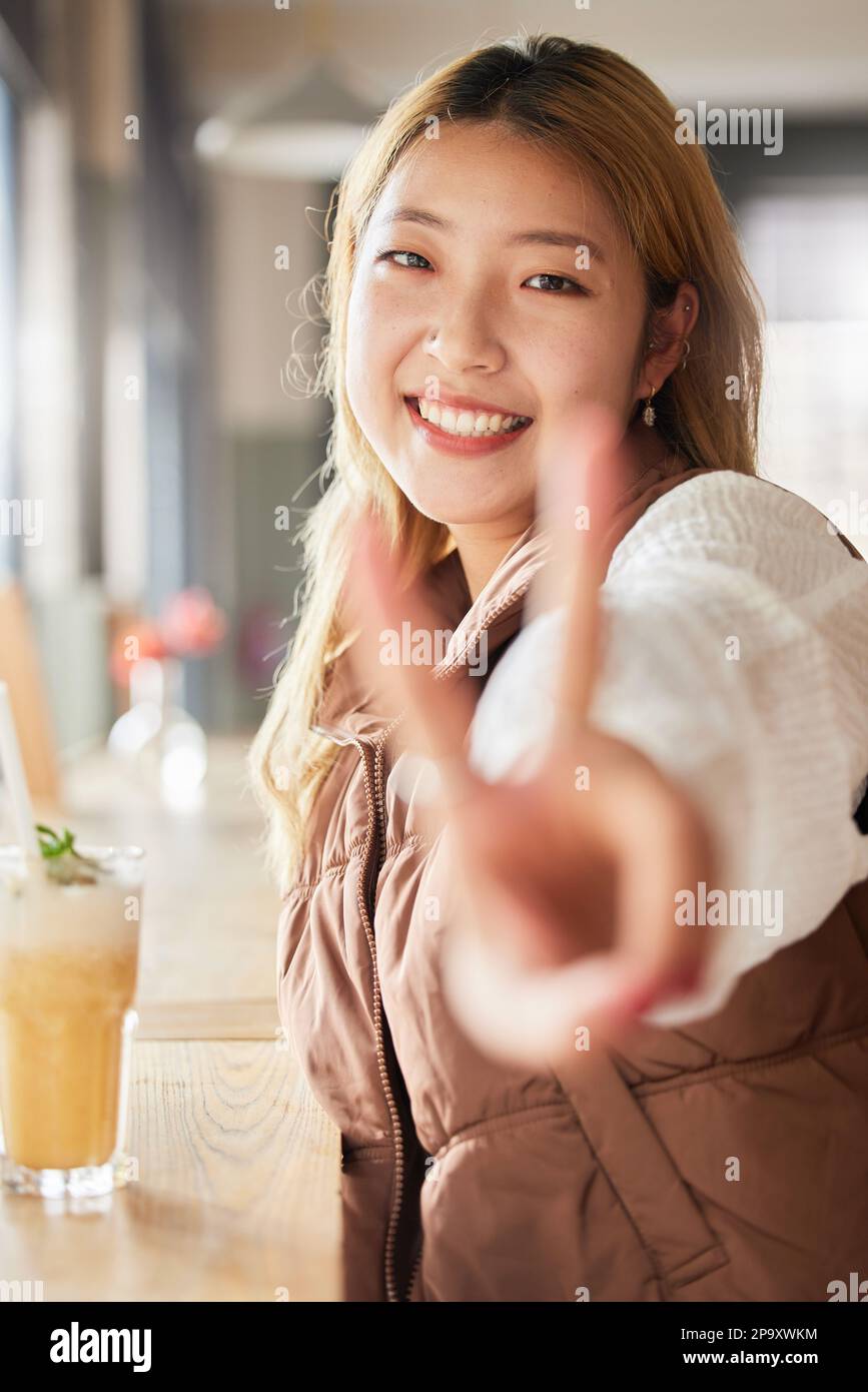 Peace, hand gesture and portrait with an asian woman in a coffee shop