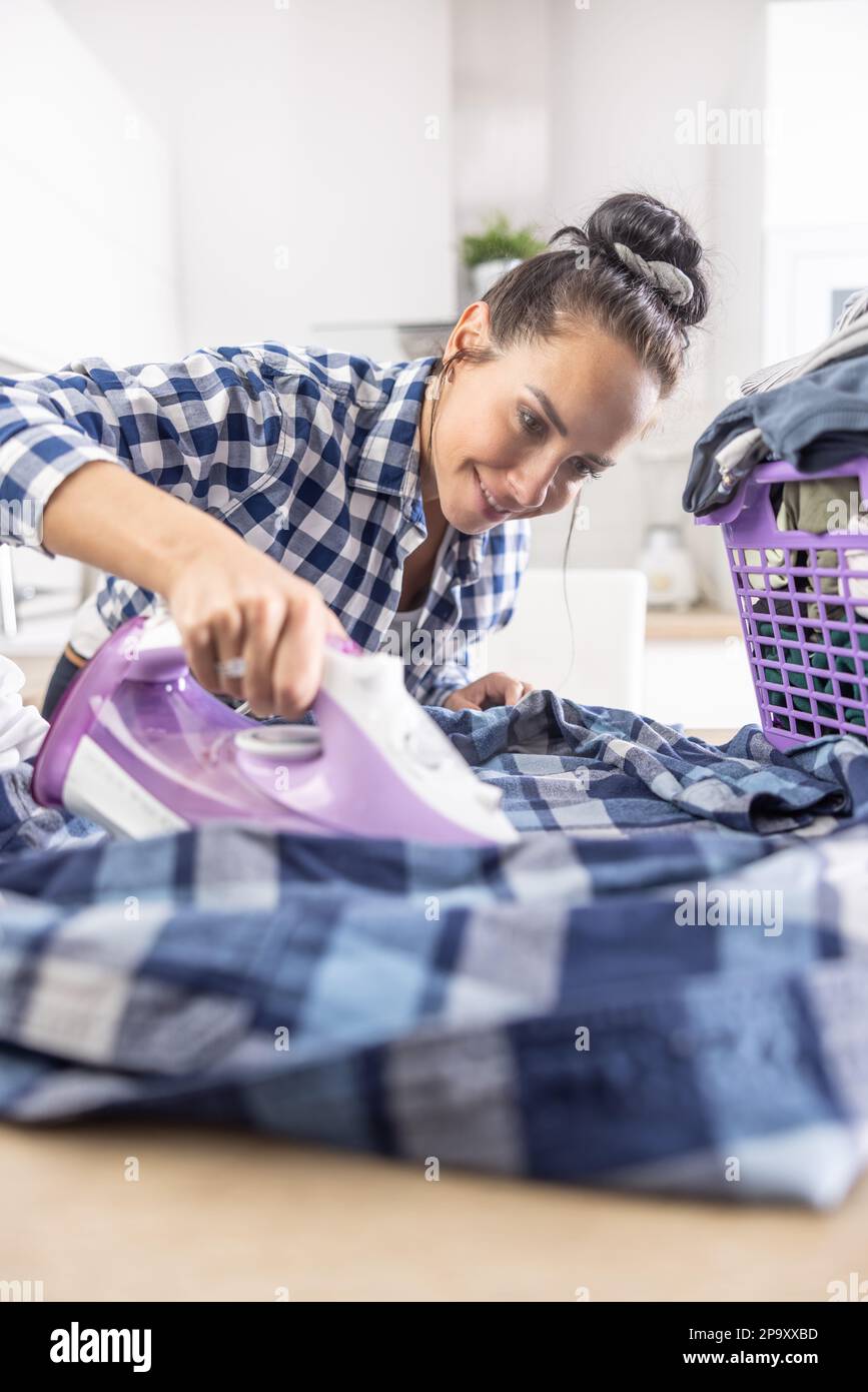 Brunette takes pride in precision ironing of a shirt during the chores at home. Stock Photo