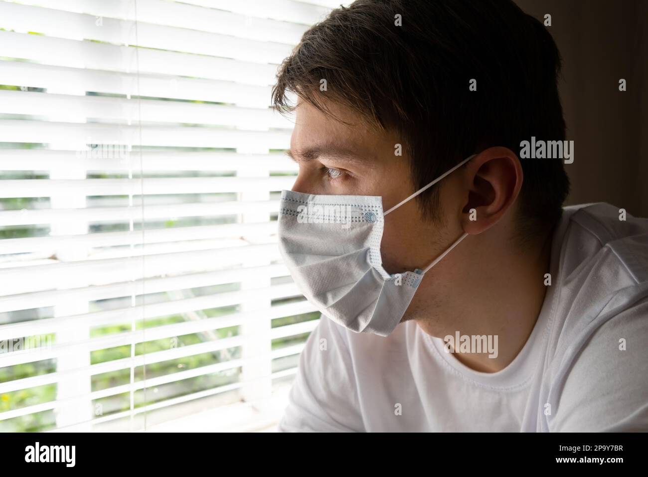 Sad Young Man in a Surgical Mask by the Window in the Room Stock Photo ...