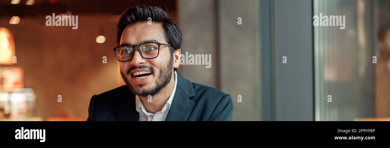 Smiling businessman working with graphs and charts at modern cafe and looking at side Stock Photo