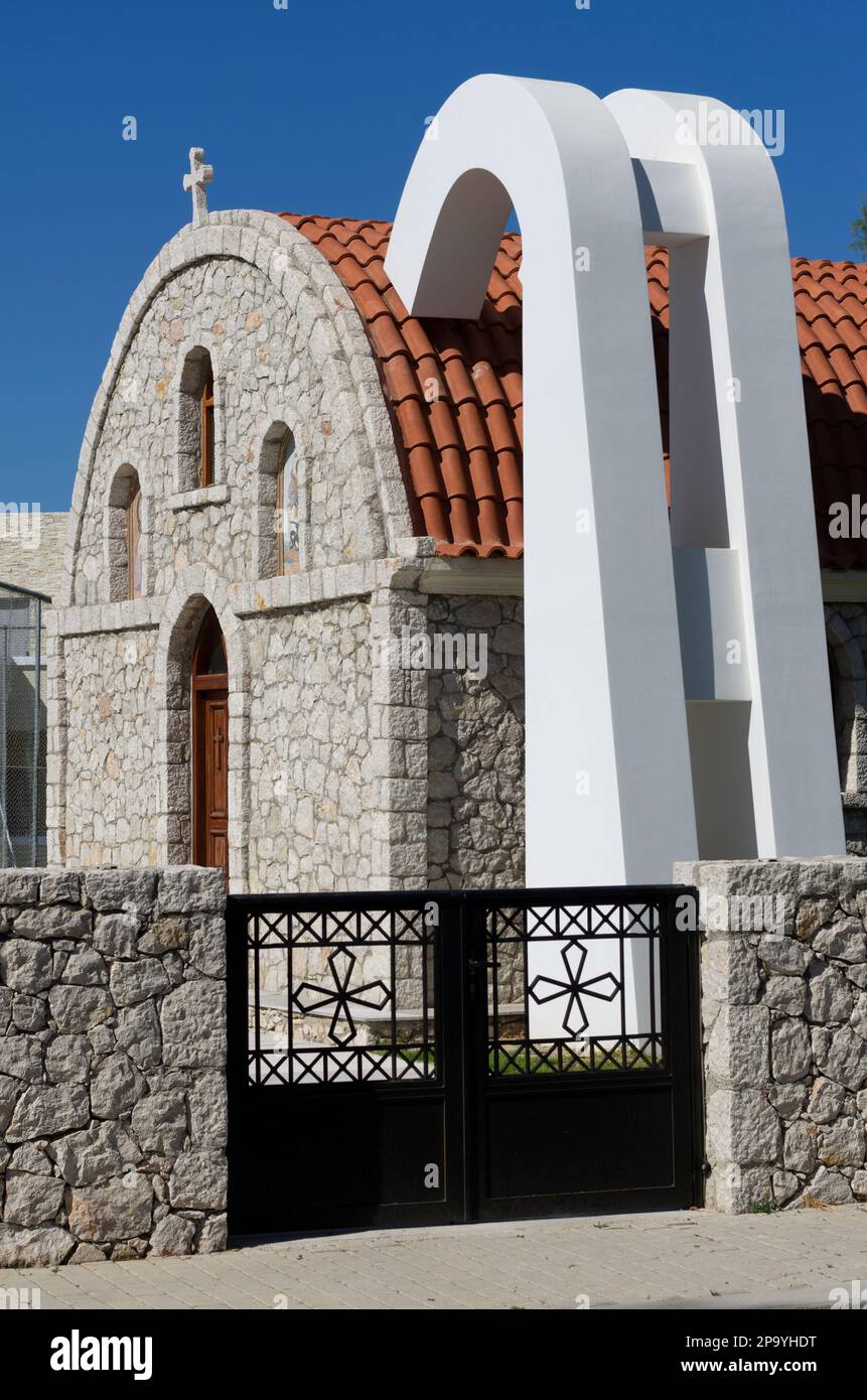 Kolymbia, Rhodes, Greece - May 25, 2019: Stone Stone Orthodox church with utilities hidden in white pylons behind a stone fence and gate Stock Photo