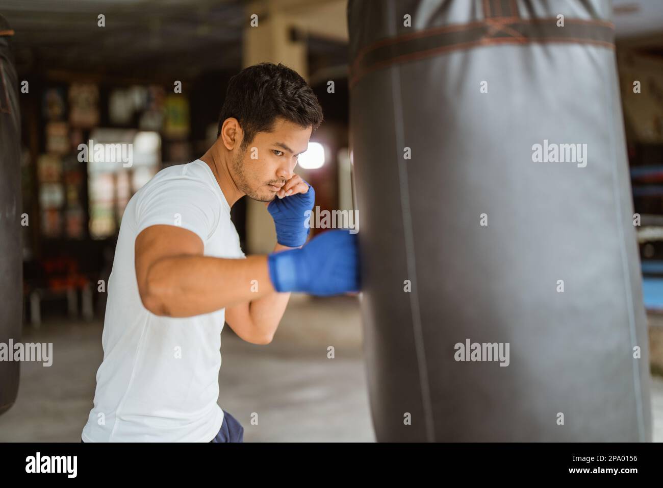 boxer seriously punching the heavy bags in the ring Stock Photo