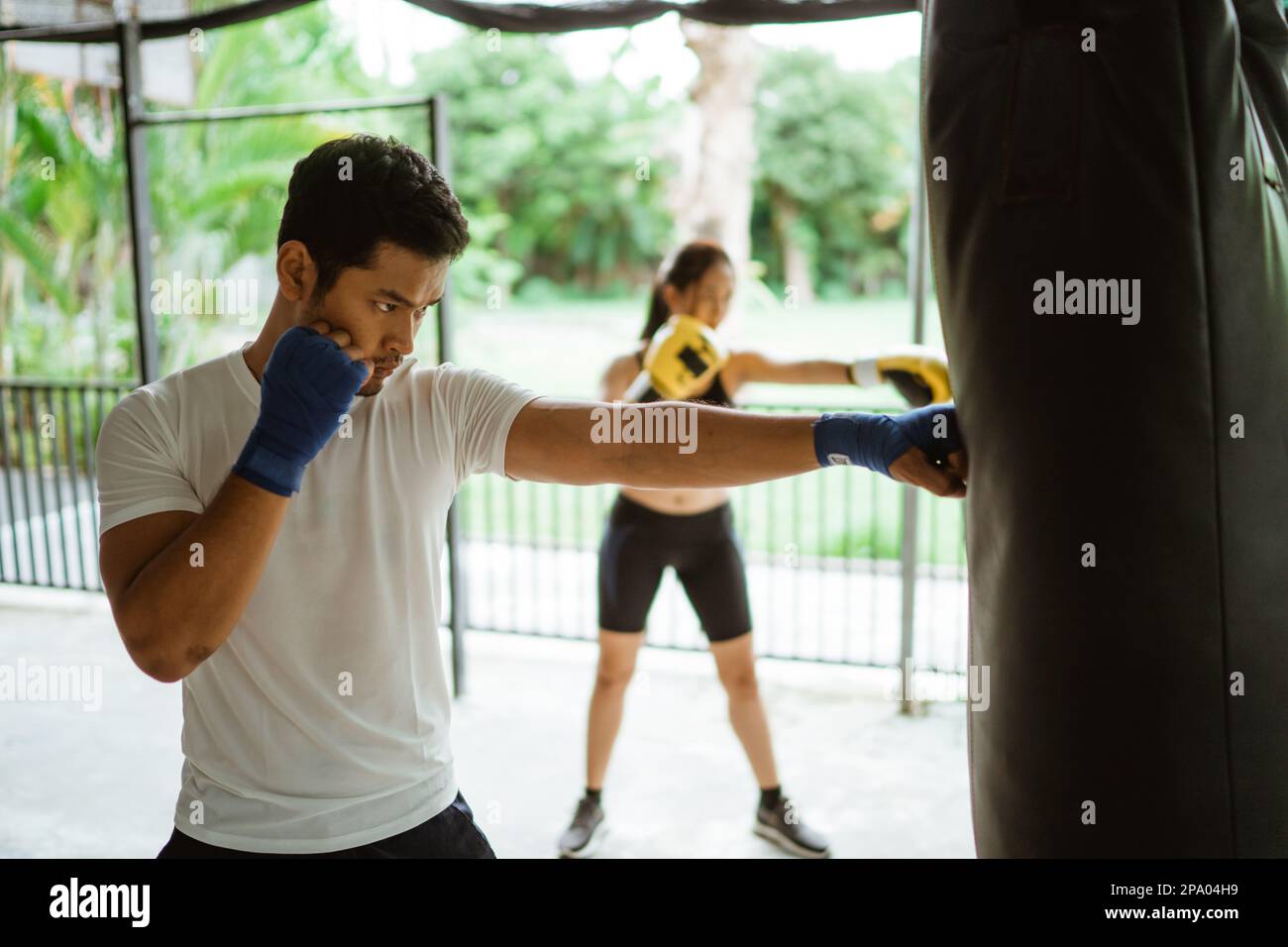 the male and female boxer hitting the sand bag Stock Photo