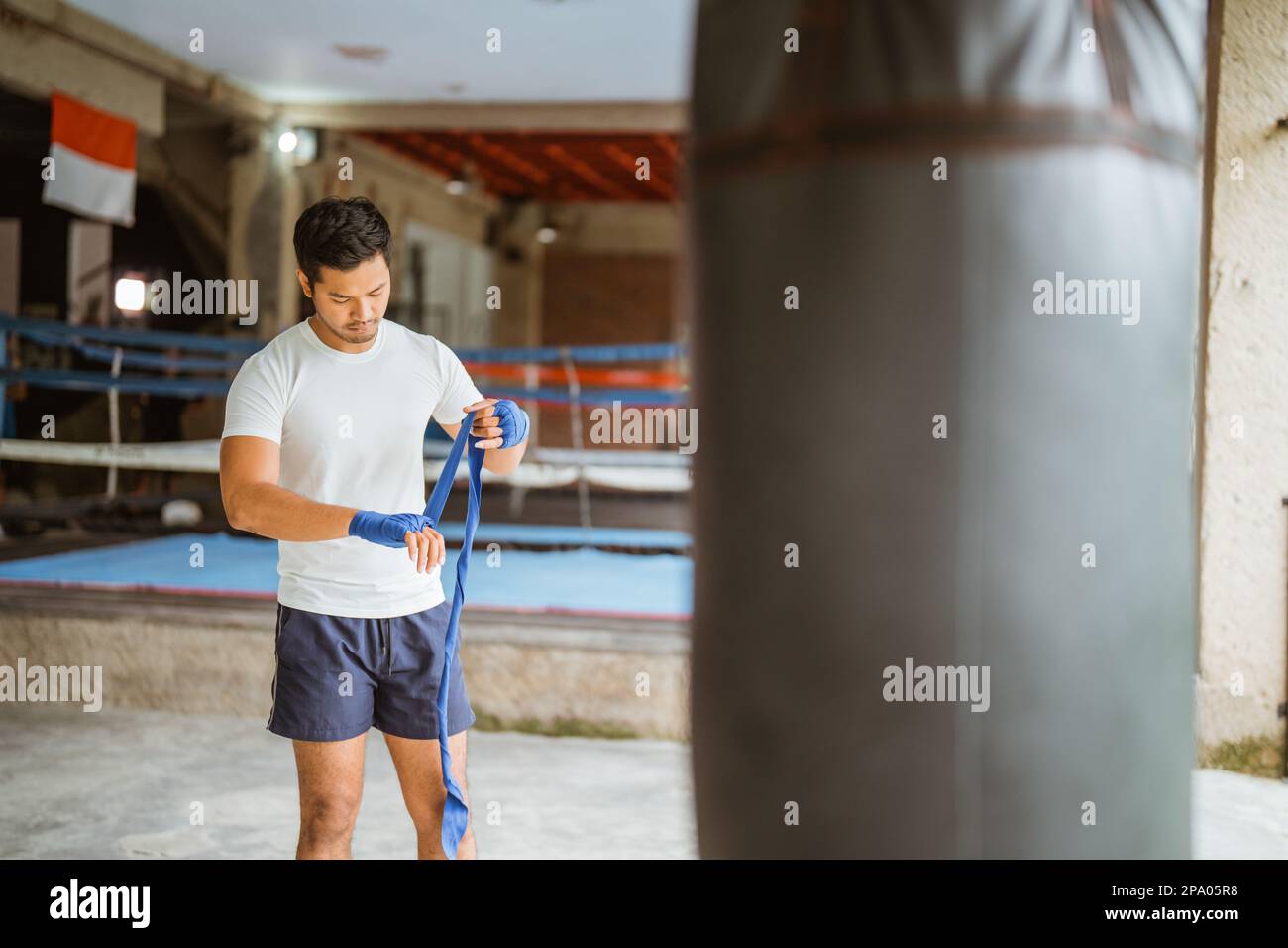 a asian male boxer wearing the boxing gloves while standing in ring Stock Photo