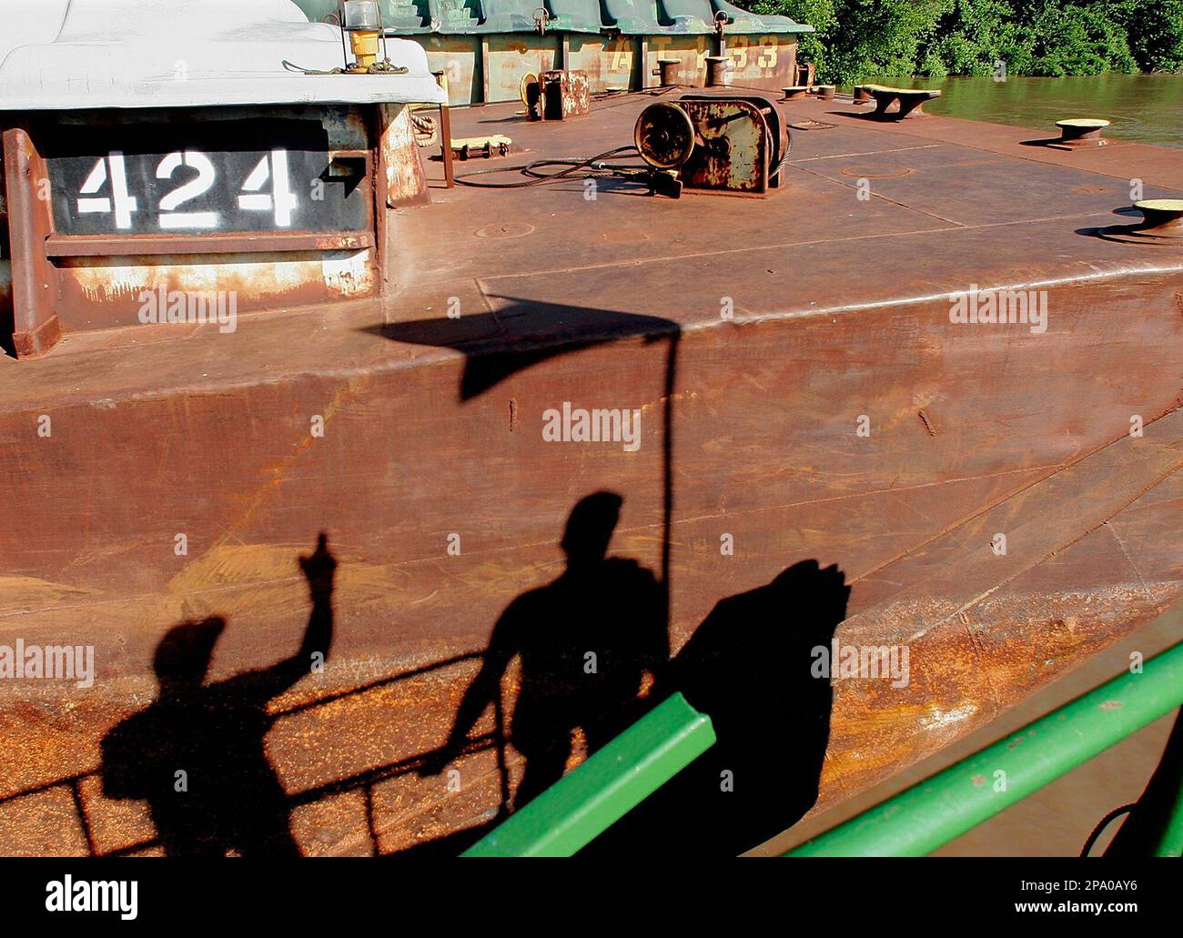 The shadow of two towboat deck hands appears on the side of a barge as ...