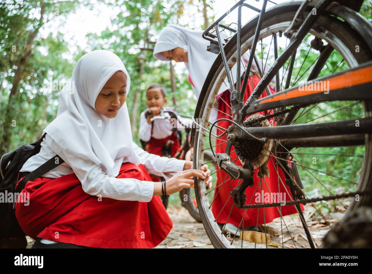 a female elementary student in uniform checking her bicycle tire Stock Photo