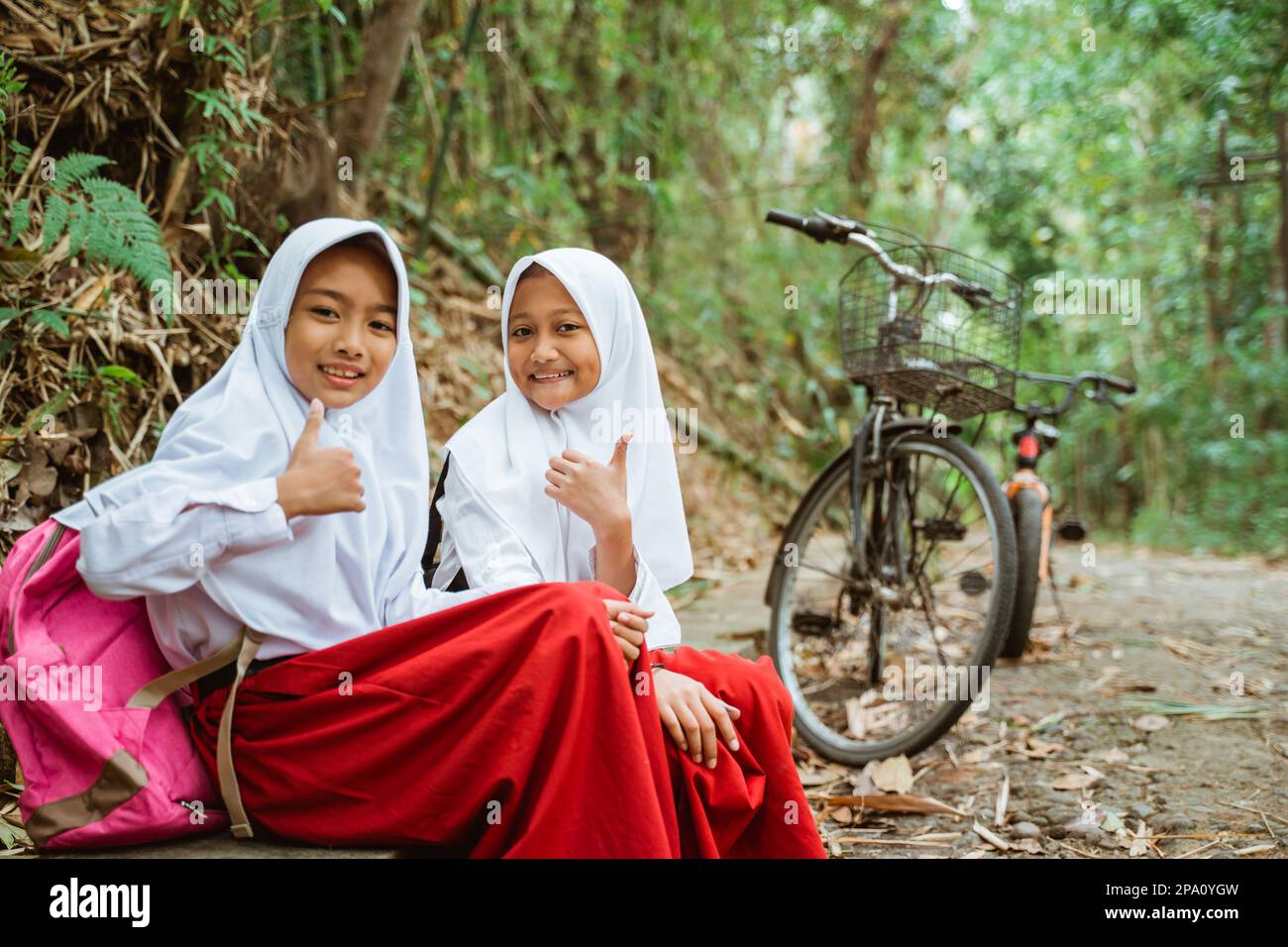 two female students sitting together with thumbs up Stock Photo - Alamy