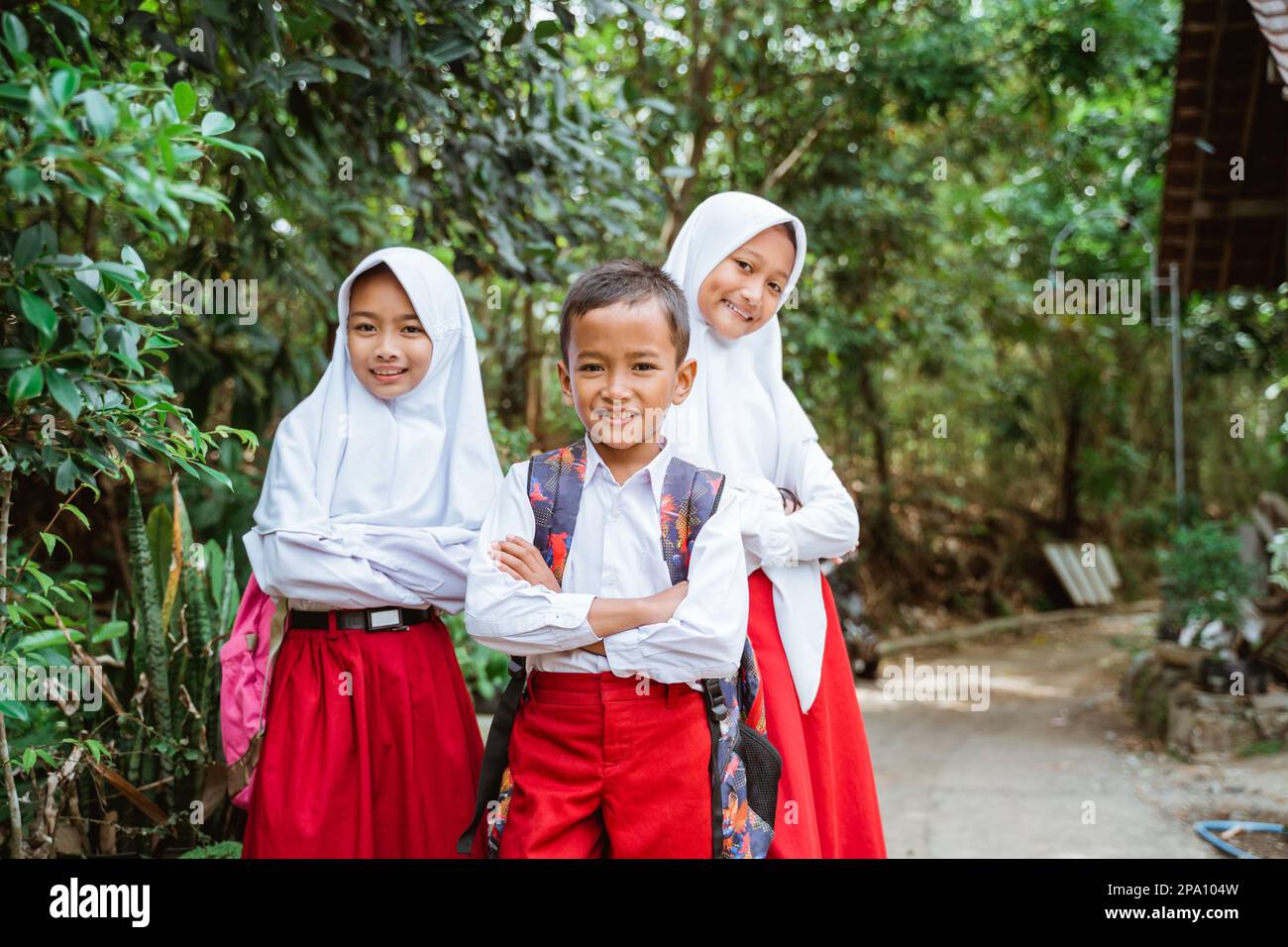 three elementary students standing at the side of country road crossing their hands Stock Photo