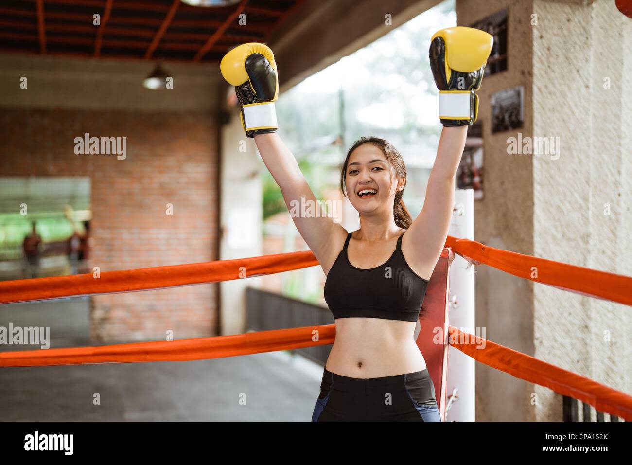 female boxer raising her hands at the corner of the box ring Stock Photo