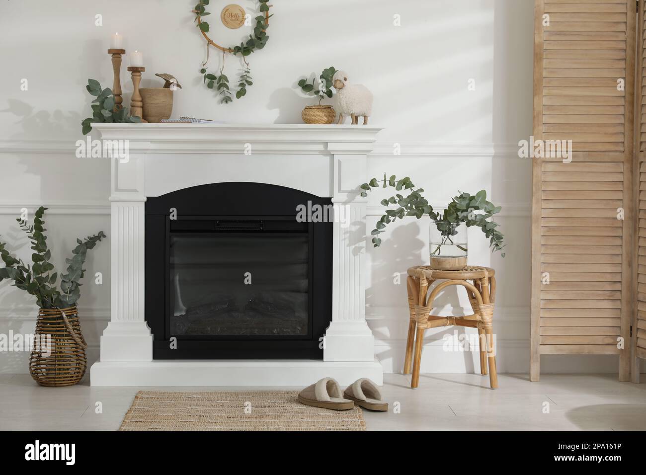 Stylish room with beautiful fireplace and eucalyptus branches Stock