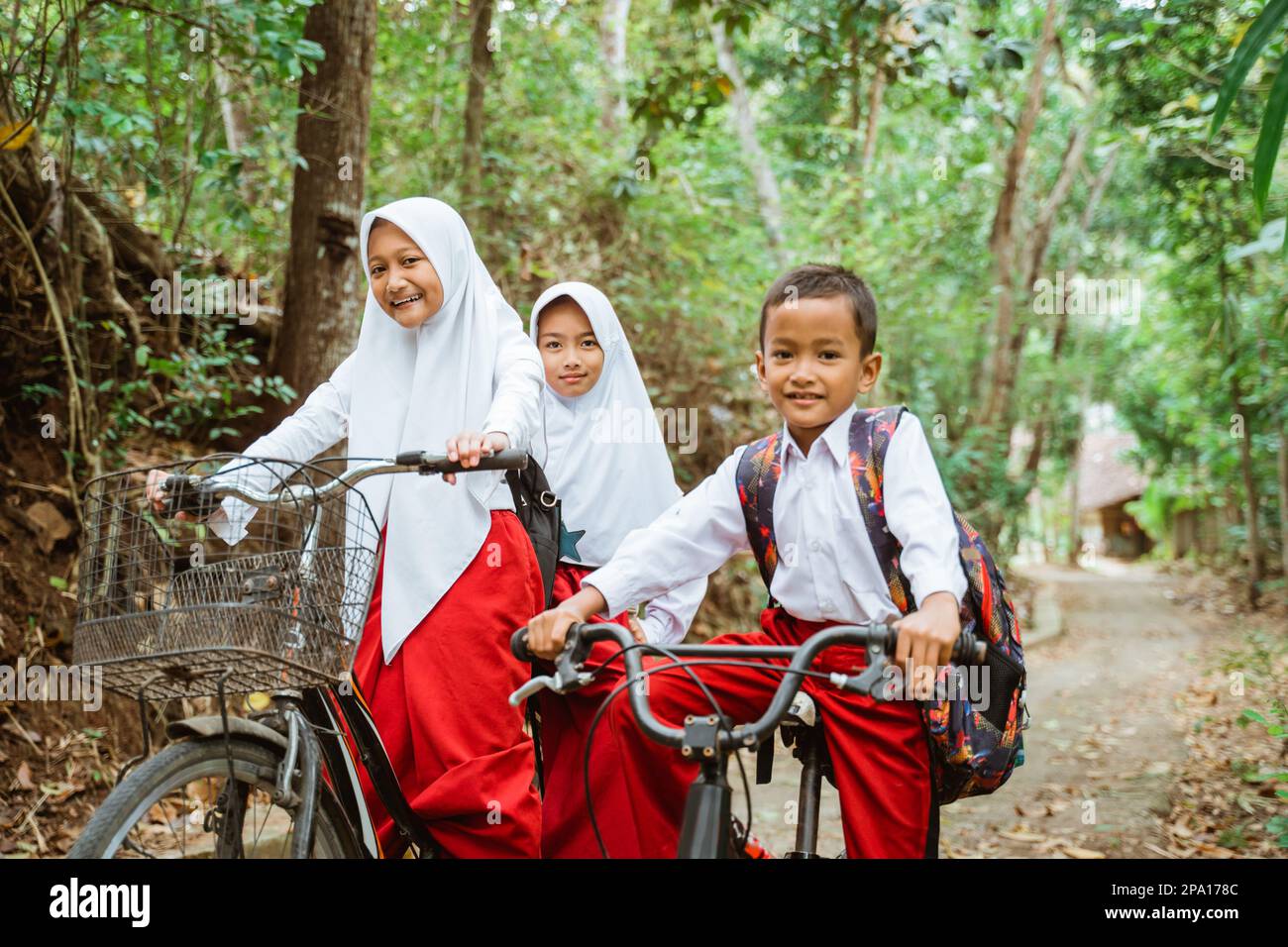 three elementary students in uniform riding their bike Stock Photo