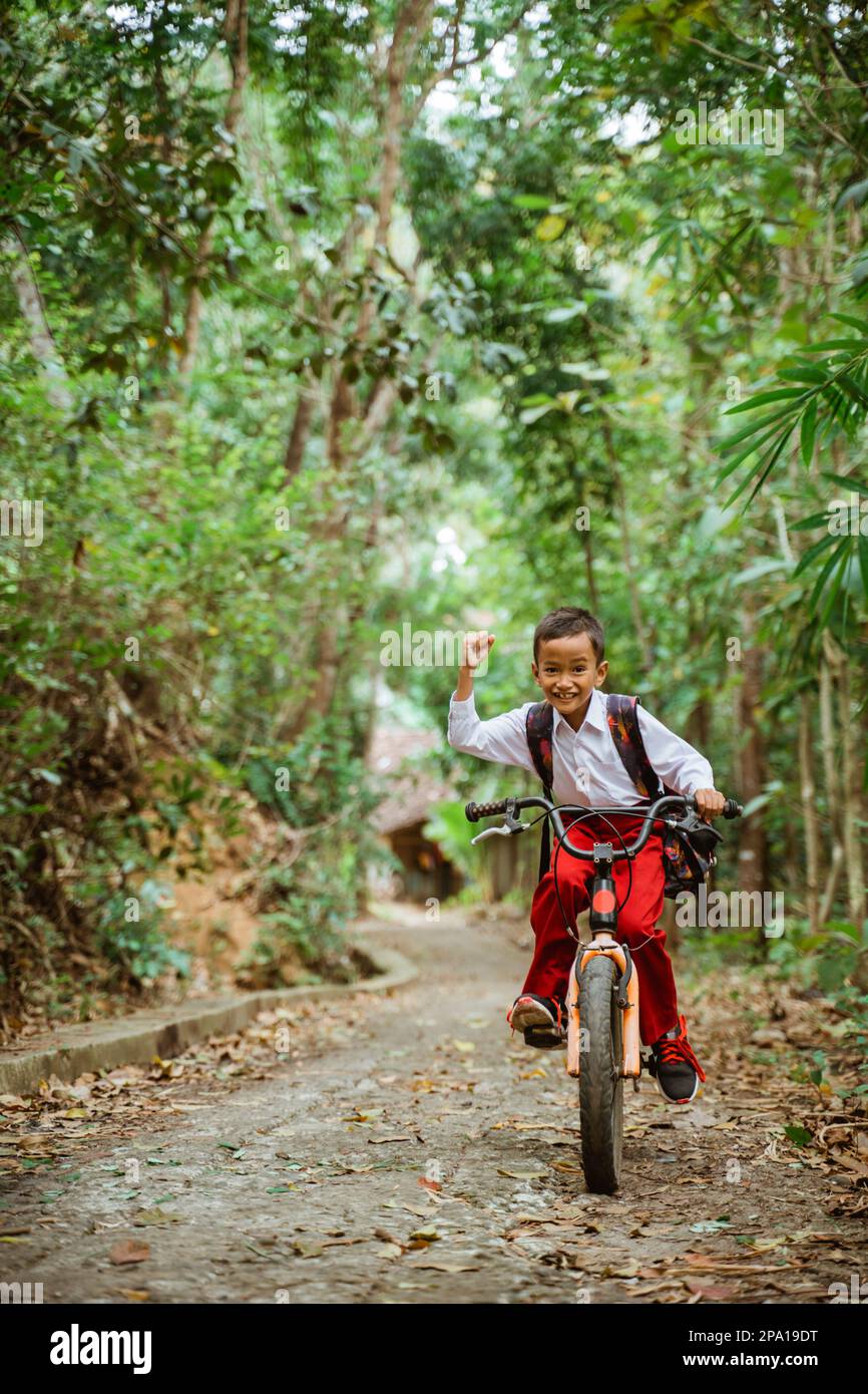 a male elementary student riding his bike and clenched his arm Stock Photo