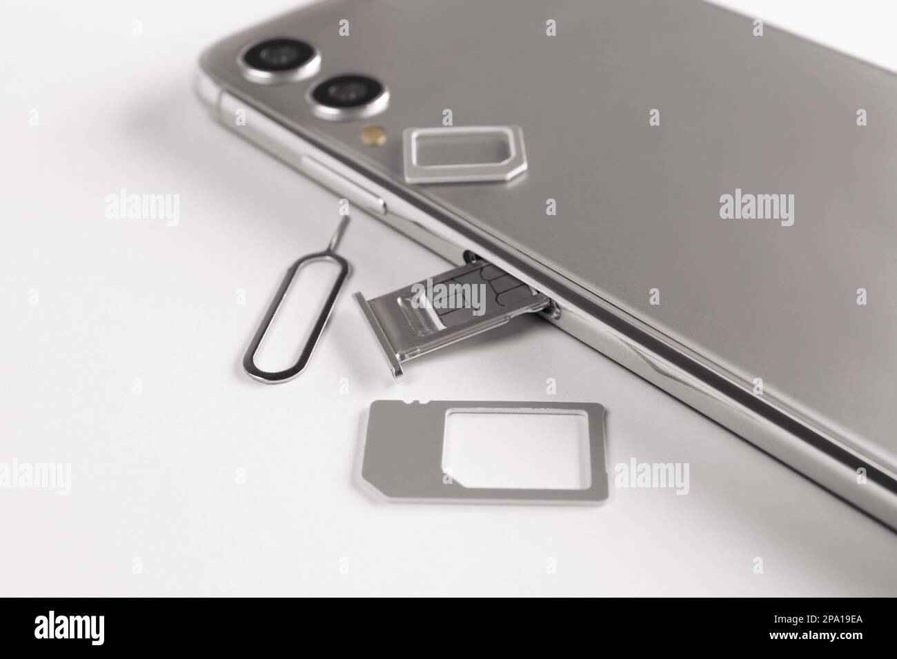 SIM card, mobile phone and ejector tool on white table Stock Photo Alamy
