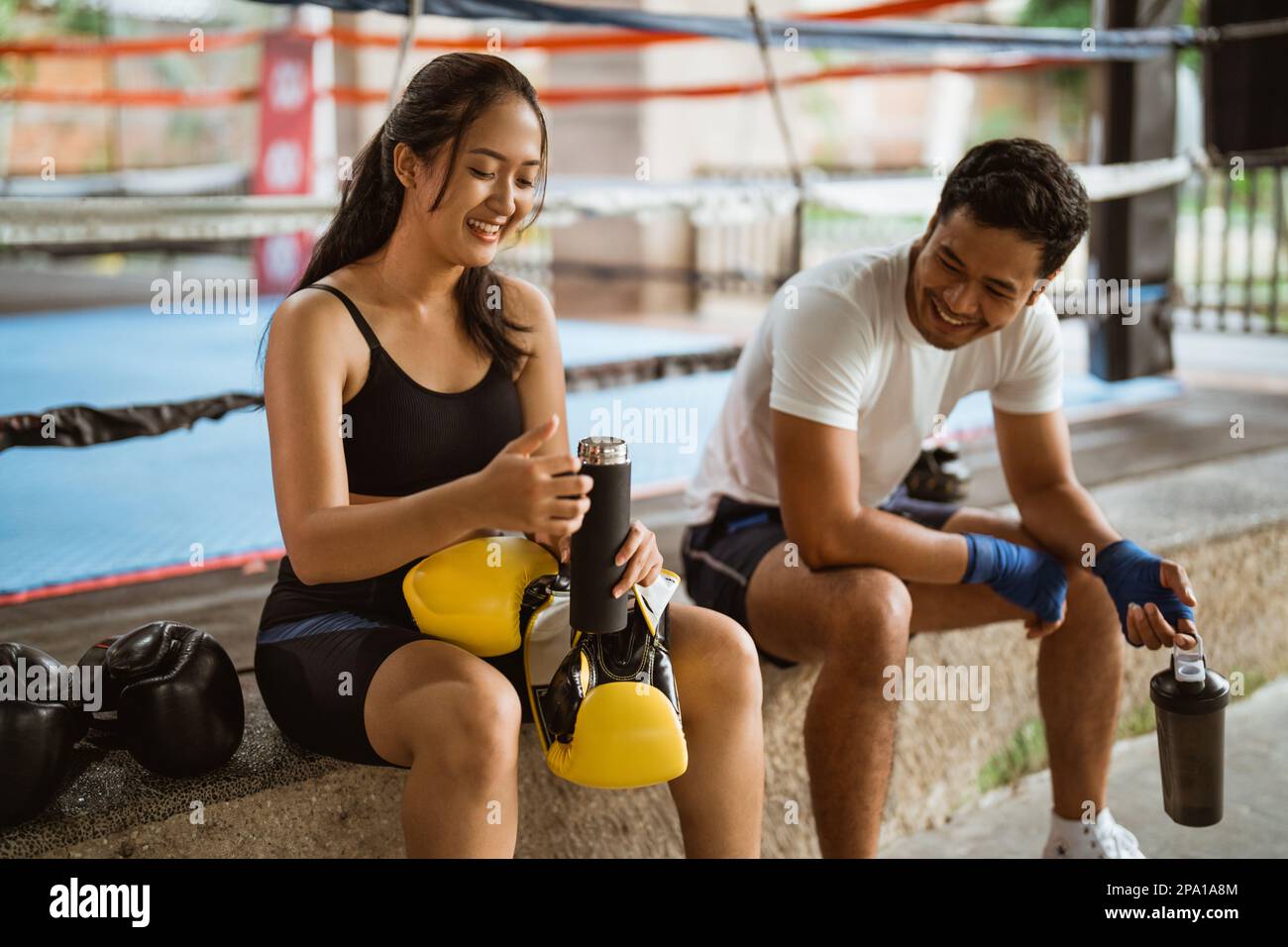 a female boxer and the male boxer sitting and laughing together Stock Photo
