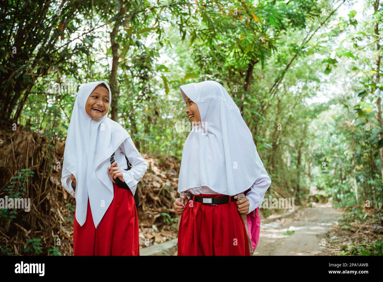 two beautiful elementary students walking together through the country road Stock Photo