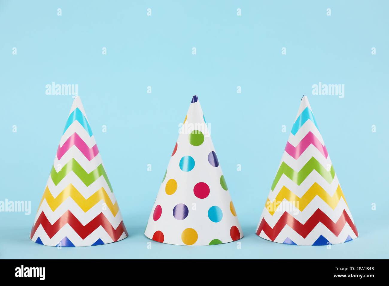 Bright party hats on light blue background Stock Photo - Alamy