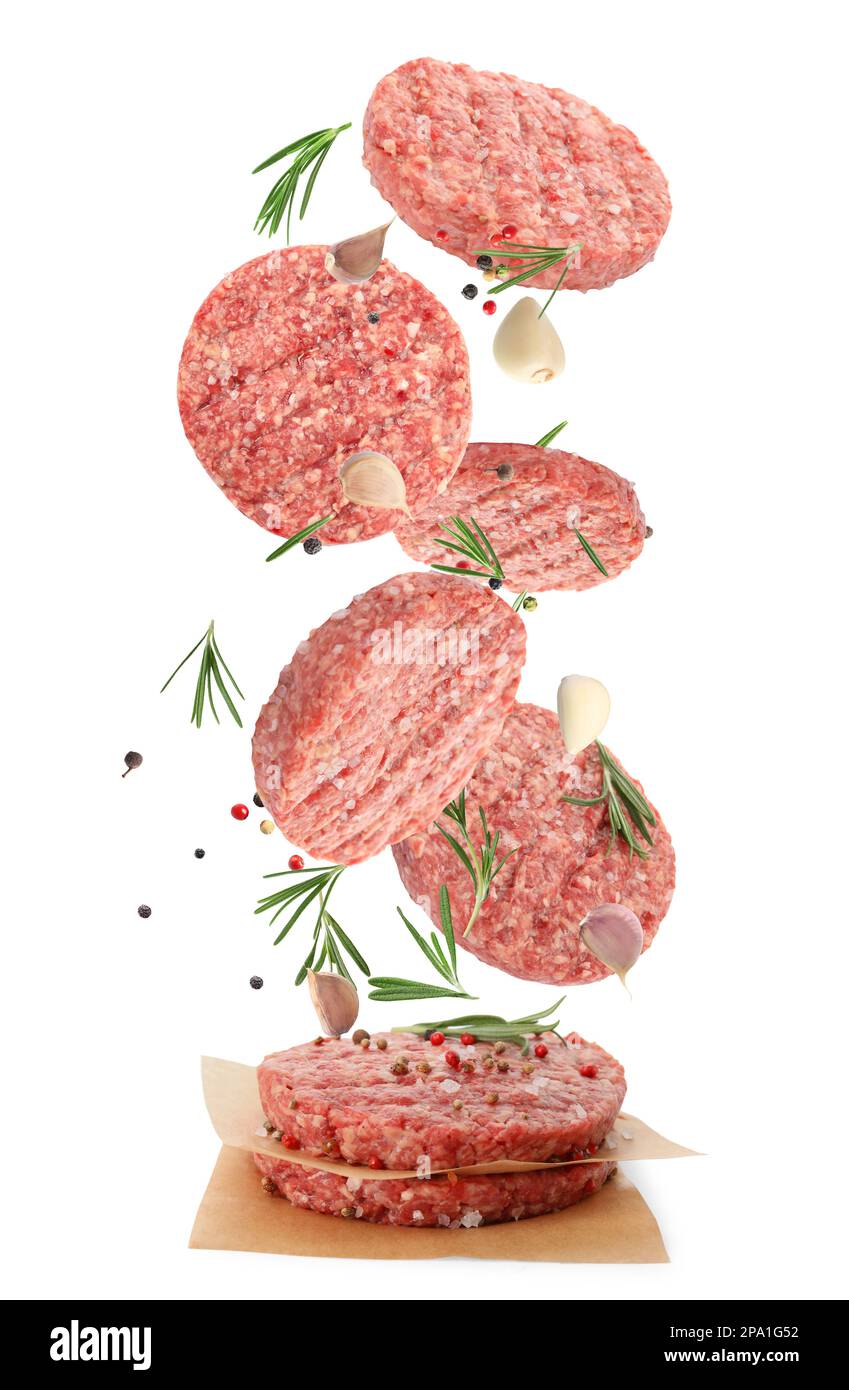 Fresh raw burger patties and seasonings falling on white background