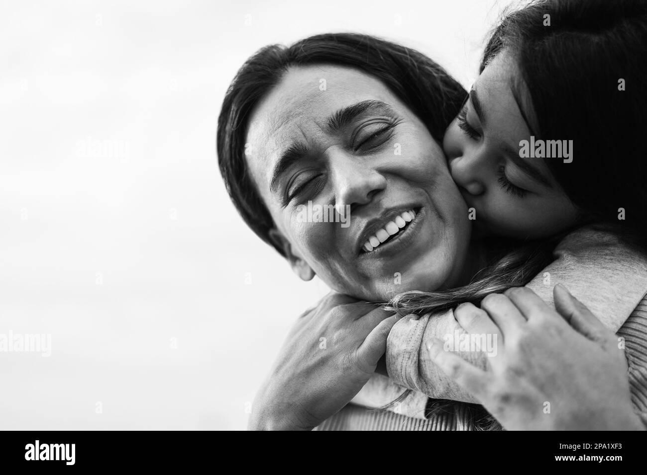 Happy latin mother and daughter having fun together outdoor - Focus on mother face - Black and white editing Stock Photo