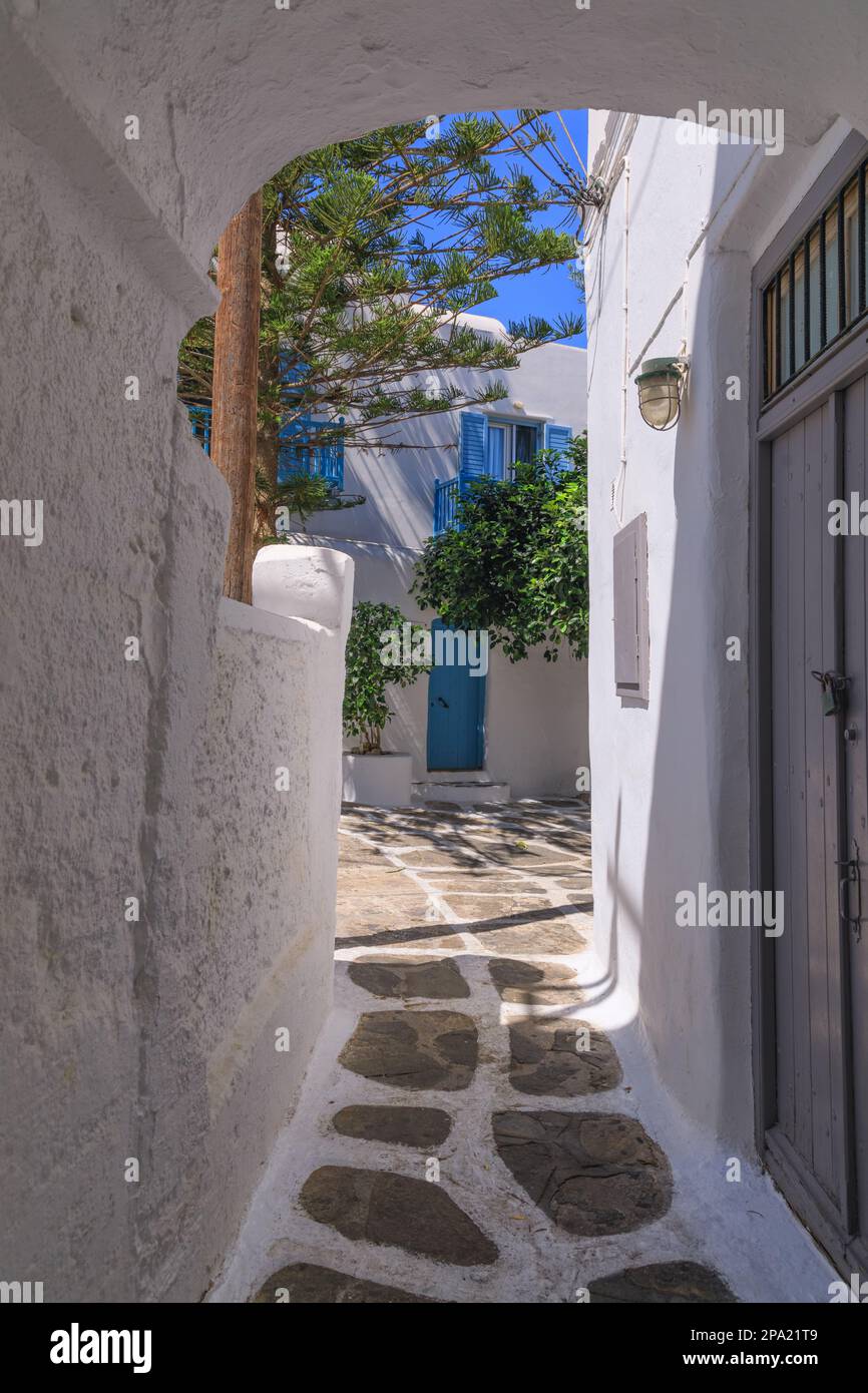 Mykonos old town in Greece: whitewashed dotted alley. Typical white Greek houses of Cyclades Islands with blue doors and windows on narrow streets. Stock Photo