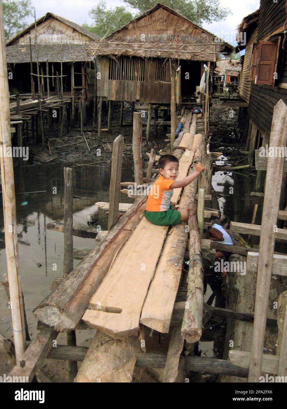 A boy in the village on Chaungtha beach in the Irrawaddy Delta region 157 km 98 miles west of Yangon Myanmar Tuesday June 3 2008 sits on the wooden bridge to his