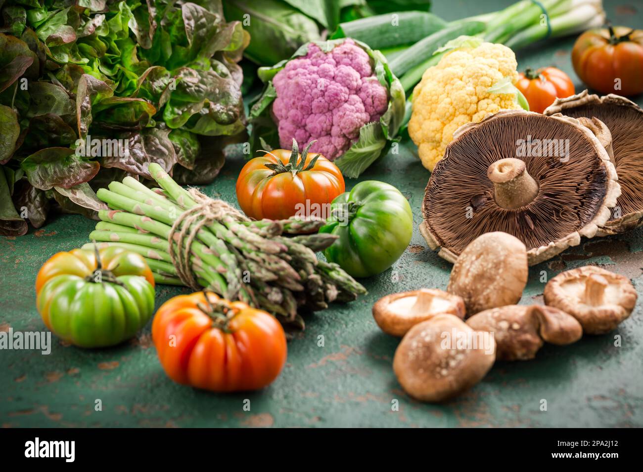 Assortment of organic vegetables and edible mushrooms on green background Stock Photo