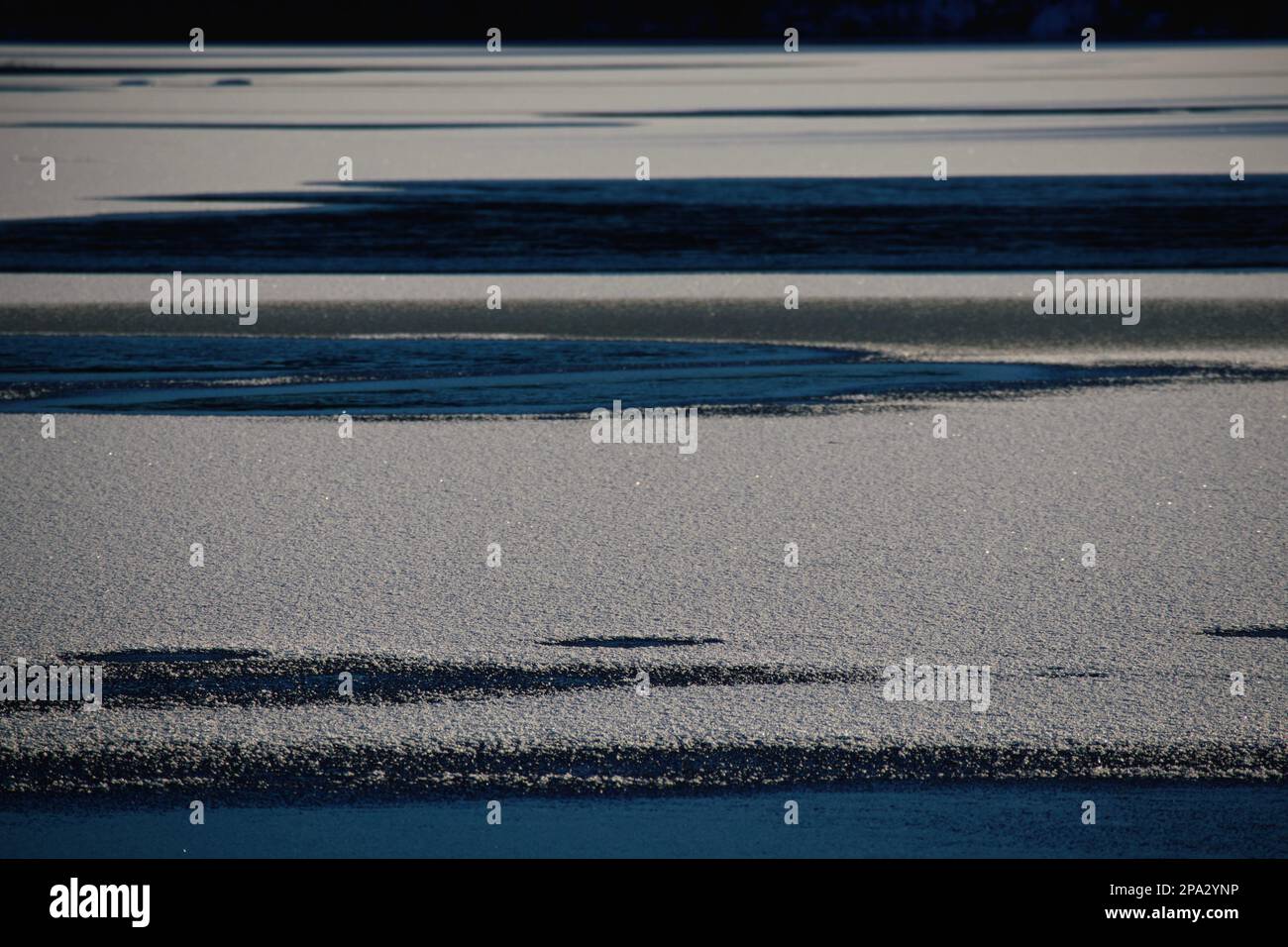 The half-frozen lake where ice part, covered with snow contrasts with the blue waters. Stock Photo