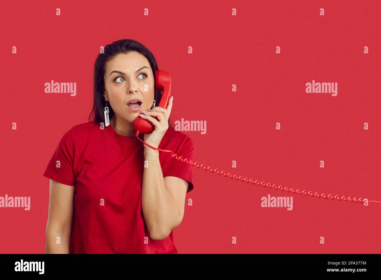 Amazed woman listens to interesting information while talking on