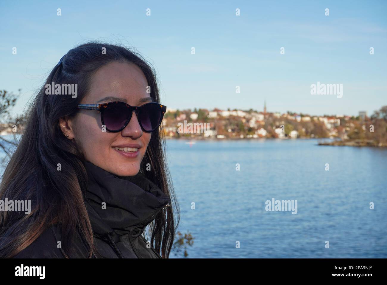 Portrait of smiling woman wearing sunglasses against lake Stock Photo ...