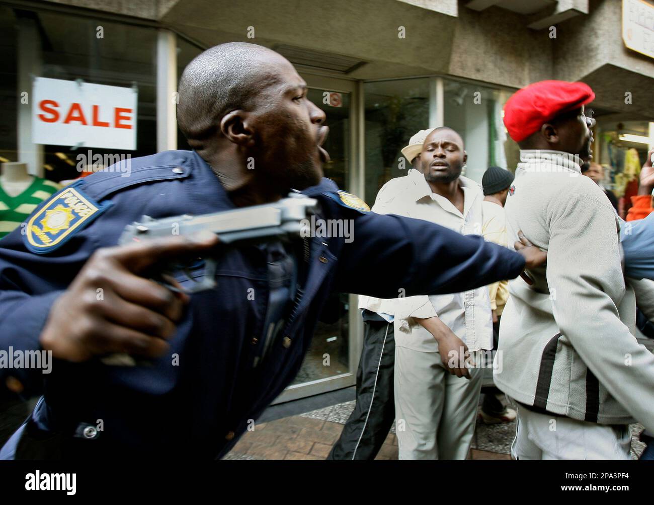A South African police officer tells foreign refugees to return to the Central Methodist Church where hundreds of immigrants are staying, after South Africans attempted to attack them in Johannesburg, South Africa, Saturday May 24, 2008. Thousands of protesters marched in downtown Johannesburg to protest the recent wave of attacks against foreigners that left over 40 dead and scores homeless.(AP Photo/Jerome Delay) Stock Photo