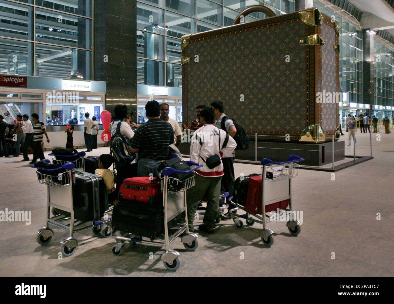 Passengers wait next to a giant suitcase outside the terminal building of  Bengaluru International Airport at its opening in Devanahalli, on the  outskirts of Bangalore, India, Friday, May 23, 2008. The Bengaluru