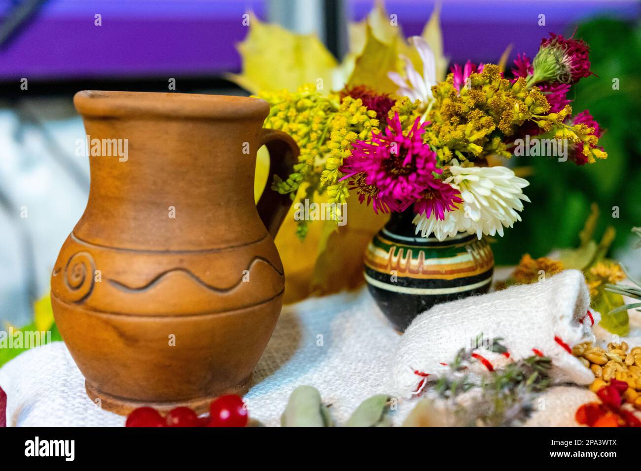 Ukrainian clay milk jug and flowers in a vase. Stock Photo